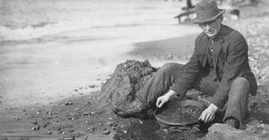 Man panning gold on Nome, Alaska, beach in the early 20th century