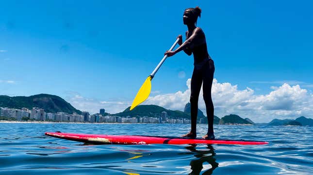 A woman standing up on a paddleboard and rowing