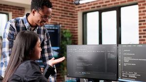 2 programmers looking at 2 screens of code
